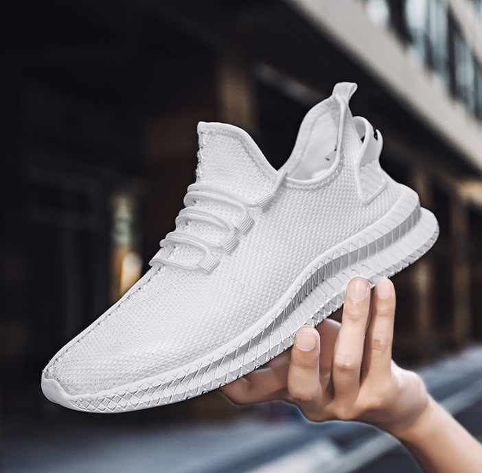 Running Shoes Sneakers Casual Men's Outdoor Athletic Jogging Sports in white design held in hand against urban background.