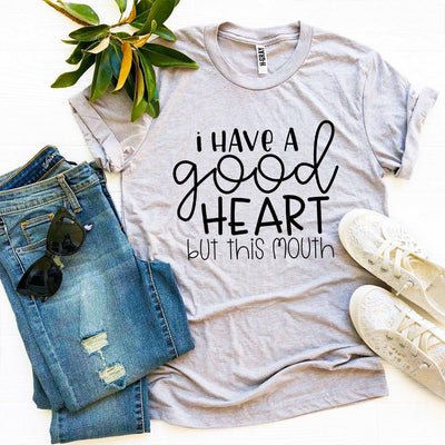 I Have a Good Heart But This Mouth T-shirt displayed on a flat lay with jeans, sunglasses, and sneakers.