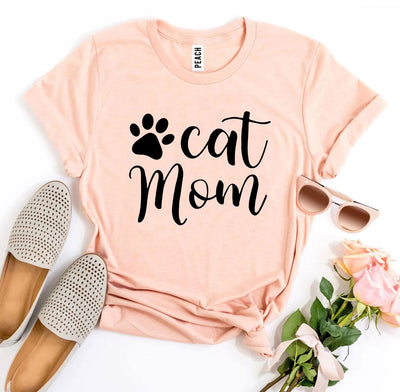 Cat Mom T-shirt in peach color with paw print design, styled with shoes and sunglasses.